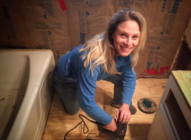 Kim Studham (Owner, Prima Construction) is installing new bathroom flooring during bathroom renovation.