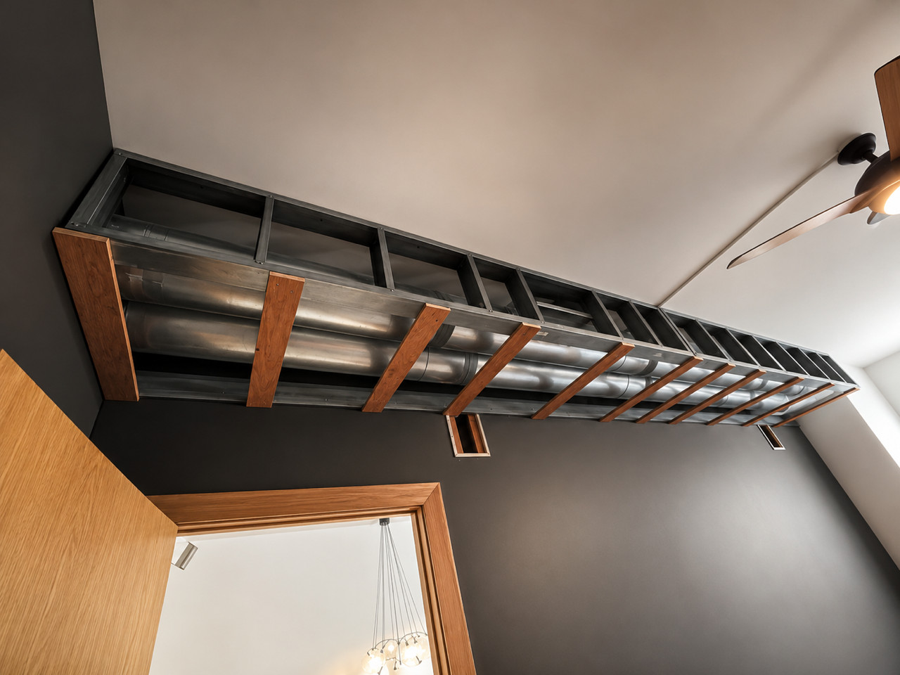 Metal-framed soffit with exposed ductwork along a ceiling, wood accents, ceiling fan.