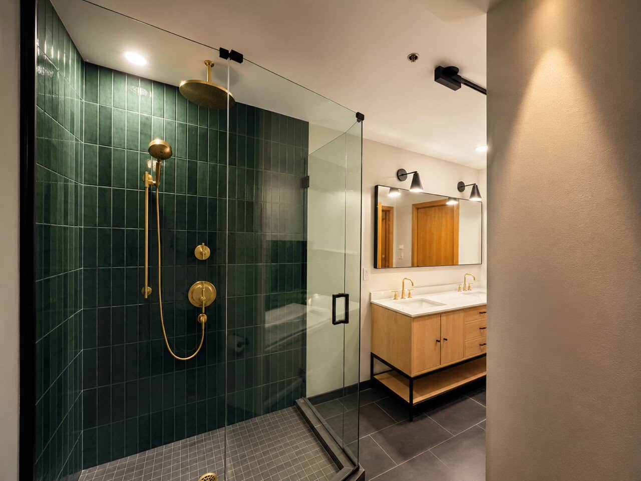 Elegant bathroom with green tiles and gold fixtures by Prima Construction.