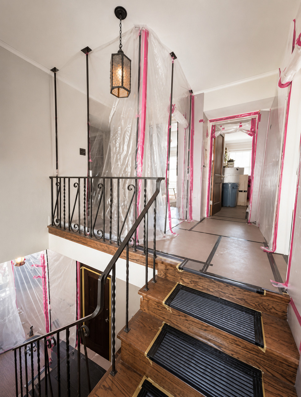Stairway and hallway covered in plastic sheeting and floor protection.