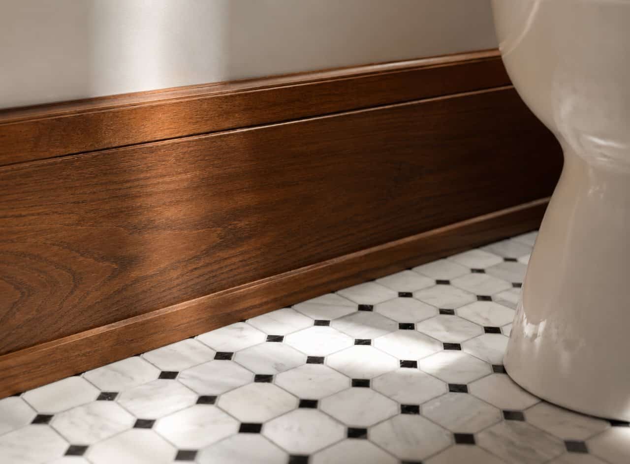 Elegant wooden baseboard in a bathroom with black and white tile floor.